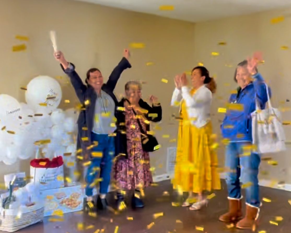 A family celebrating in the empty living room of the home they just bought